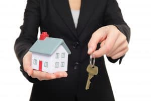 Real Estate agent holding keys and model house