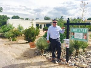 Man standing next to a for sale sign