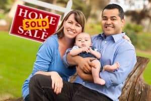 Young family in front of sold sign