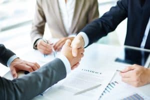 business partners handshaking over business objects on workplace